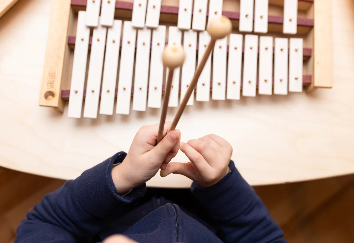 Enfant jouant du carillon en bois et métal Serclet